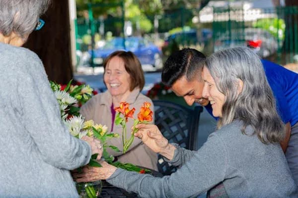 Residents and team members arrange flowers outdoors