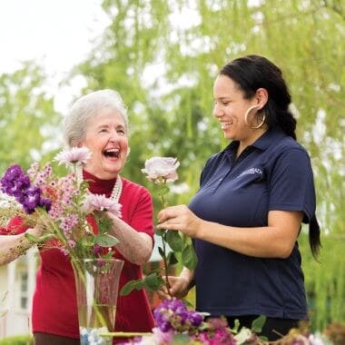 A Silverado resident and team member arranging flowers outdoors