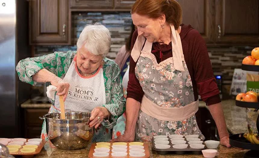 A resident and team member bake cupcakes